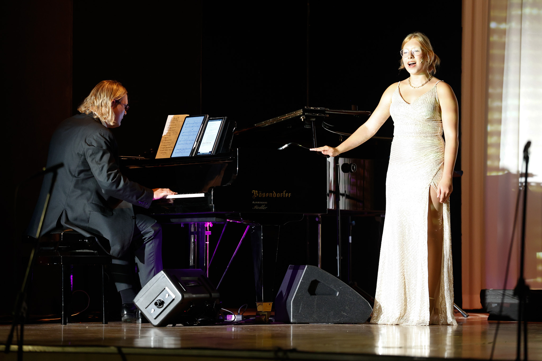 Sängerin im weißen Abendkleid singt neben dem Pianisten am Flügel